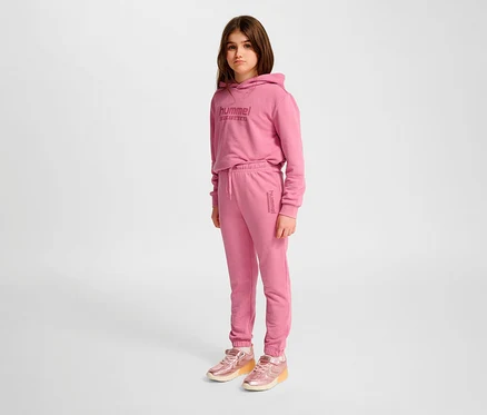 Une fille portant un pantalon régulier HUMMEL HMLJR Base rose et un sweat à capuche.