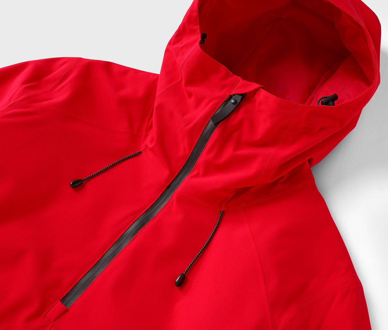 Gros plan sur une veste rouge à capuche avec une fermeture éclair noire.