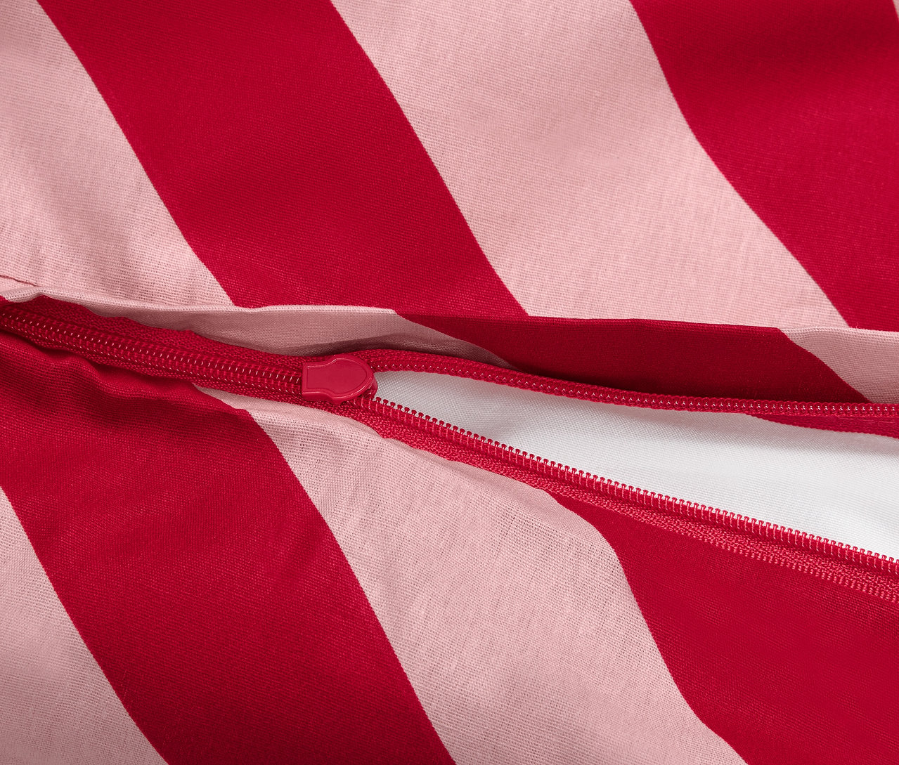 Gros plan d'une housse de couette à rayures rouges et blanches avec fermeture éclair.
