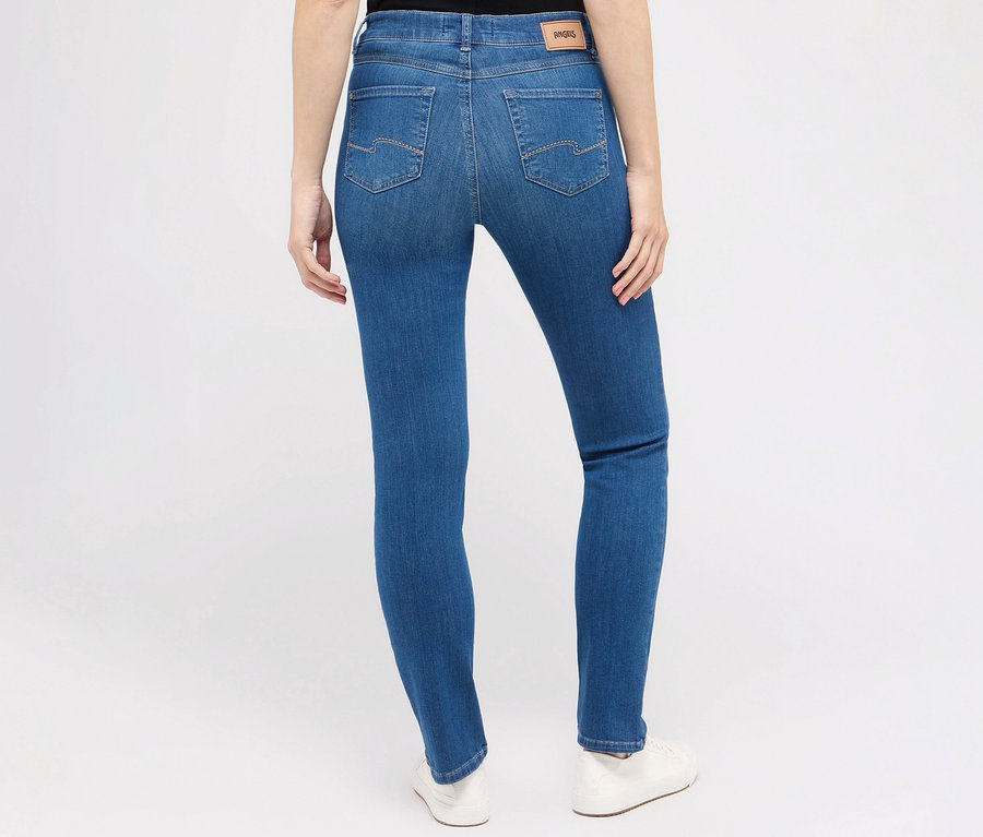 Vue arrière d'une femme portant un jean Angels « Cici » coupe étroite, bleu moyen et des chaussures blanches.