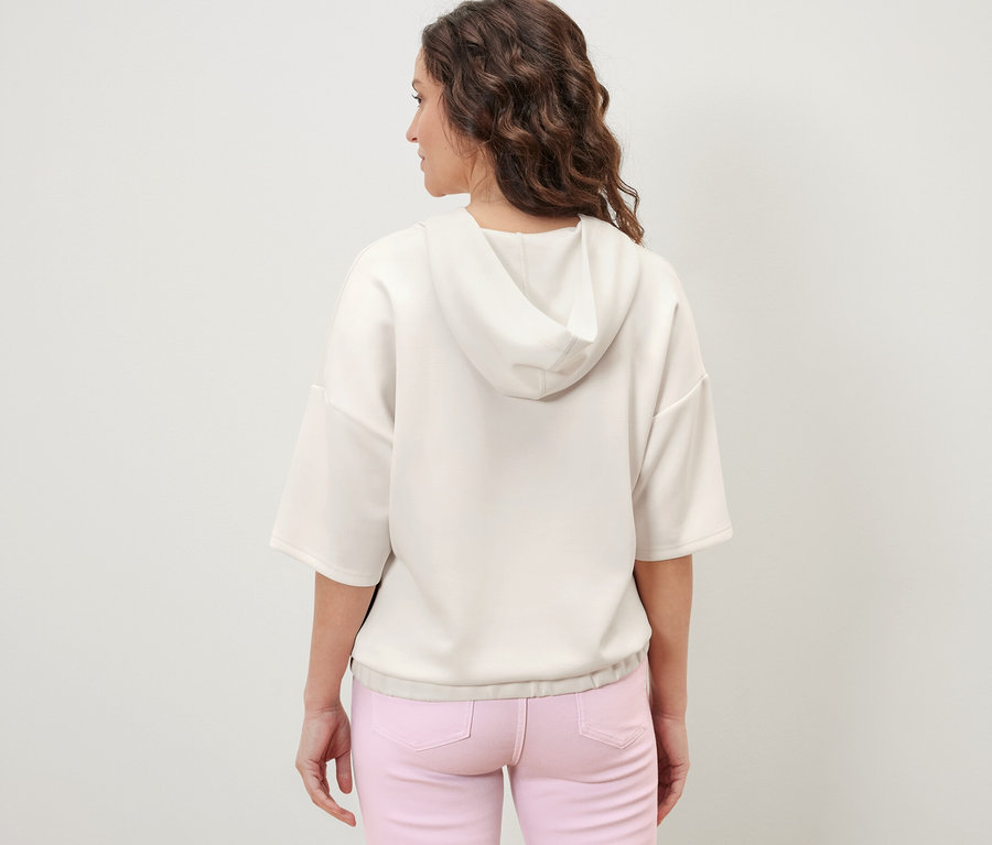 Vue arrière d'une femme portant un pull à capuche en mélange de modal crème et un pantalon rose.