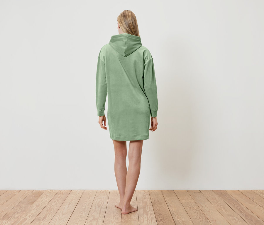 Une femme, vue de dos, porte une robe à capuche verte.