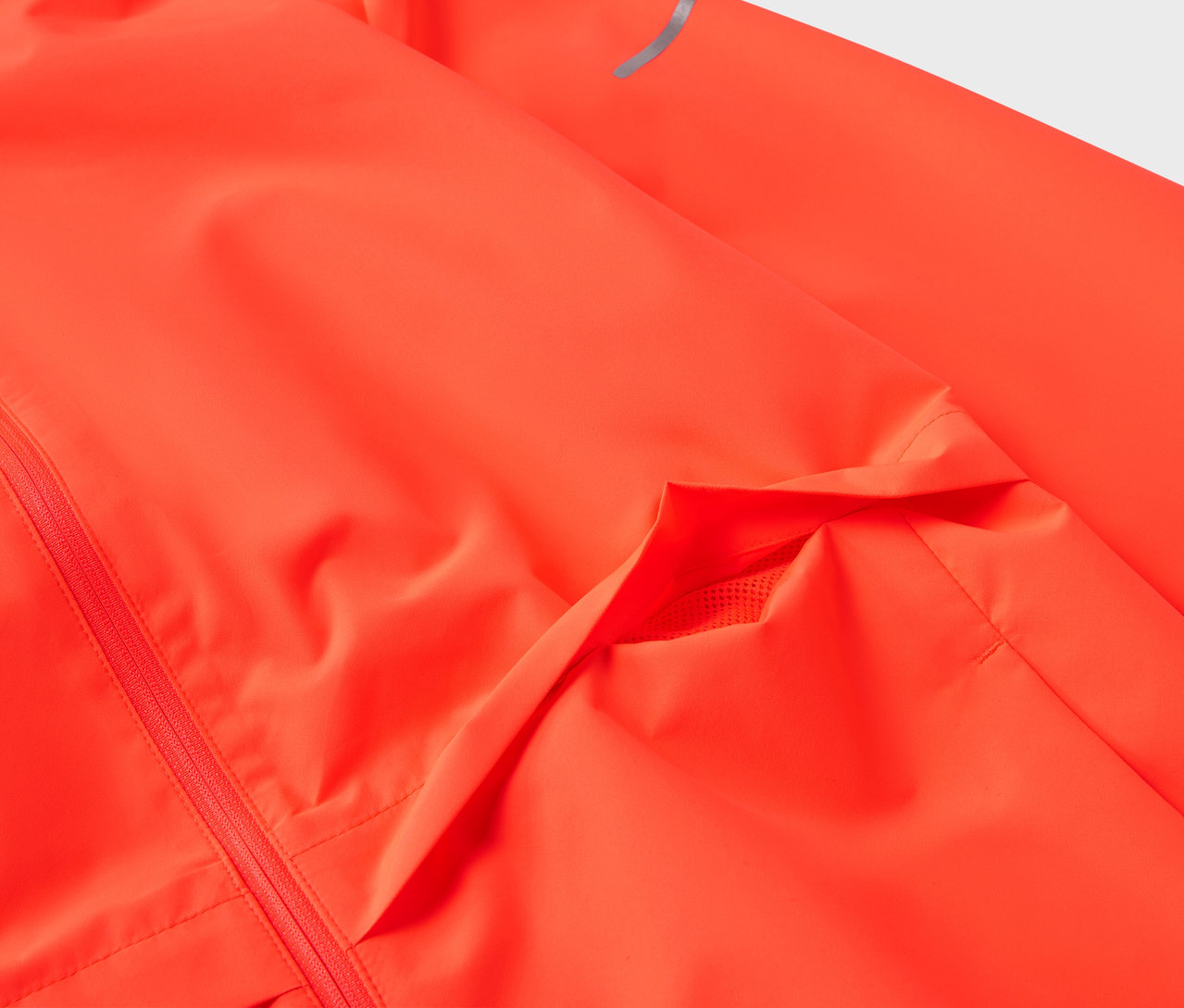 Détail d'une veste orange fluo avec une poche et une bande réfléchissante sur la manche.