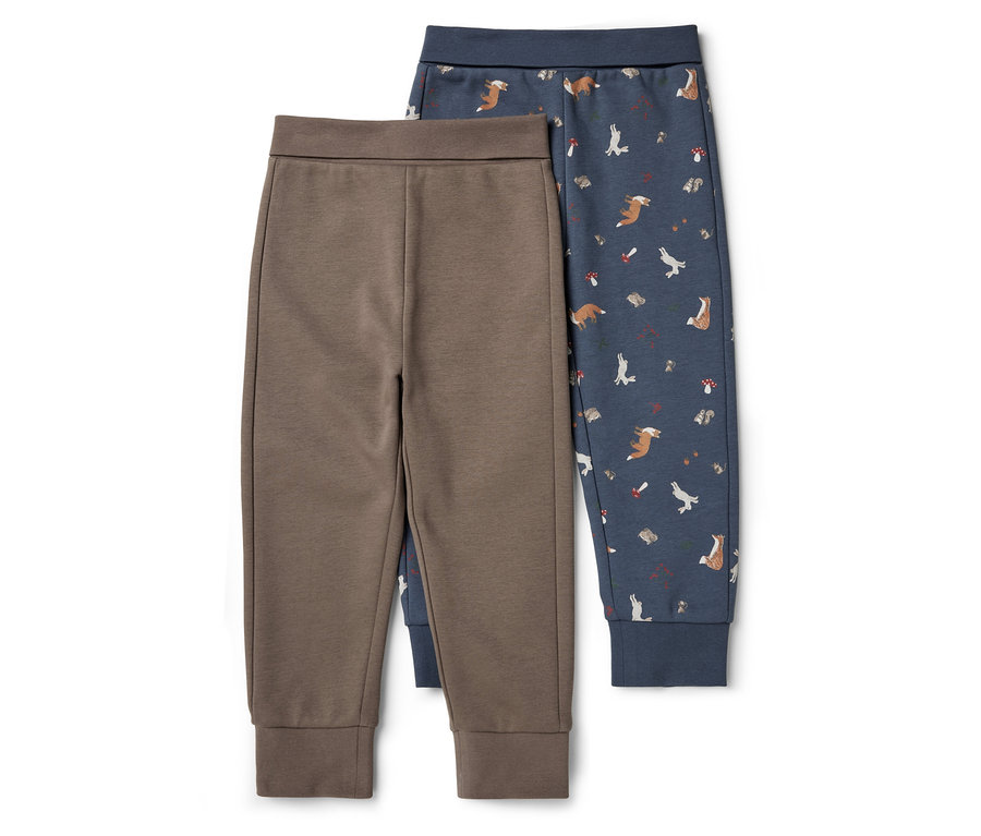 Deux pantalons de survêtement : l’un marron uni et l’autre bleu à motif de renards, de lièvres, de hérissons et de champignons.