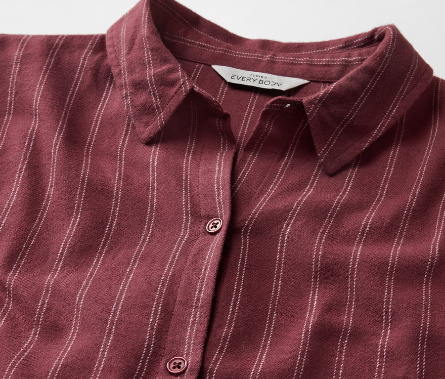 Vue détaillée d'une chemise bordeaux rayée avec col et boutons.