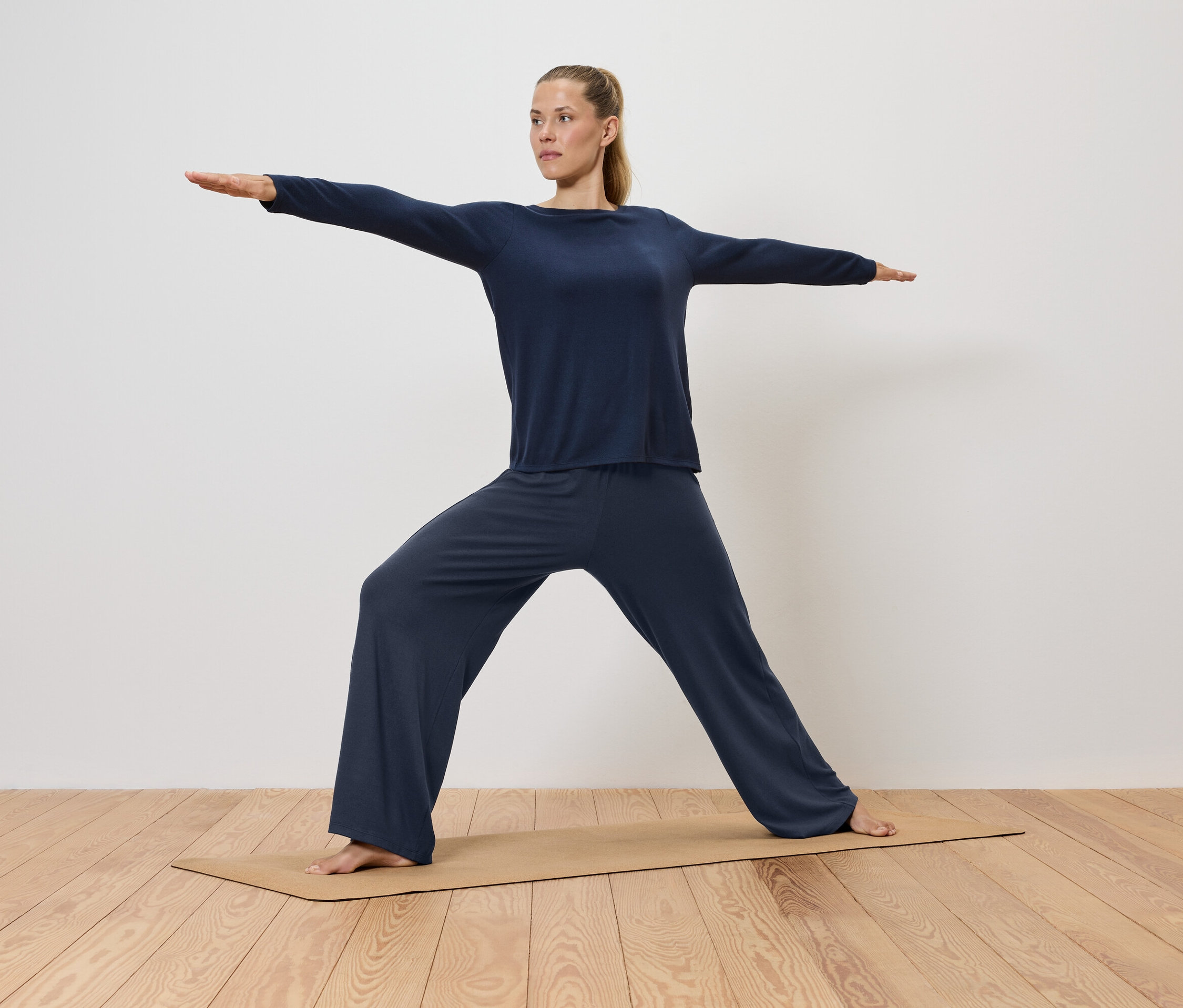 Femme en vêtements bleus faisant du yoga sur un tapis.