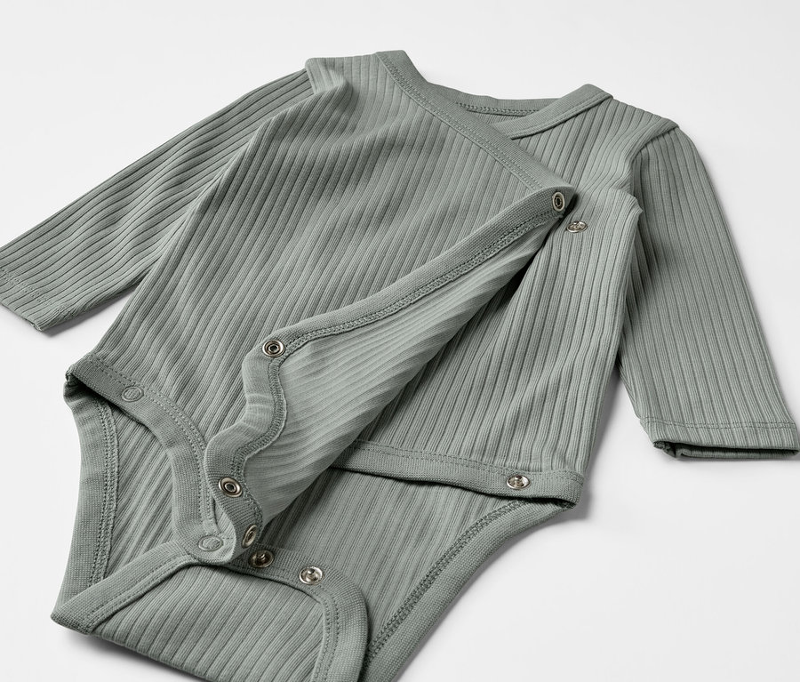 Deux bodys côtelés manches longues gris-vert pour bébé sont posés l'un sur l'autre.