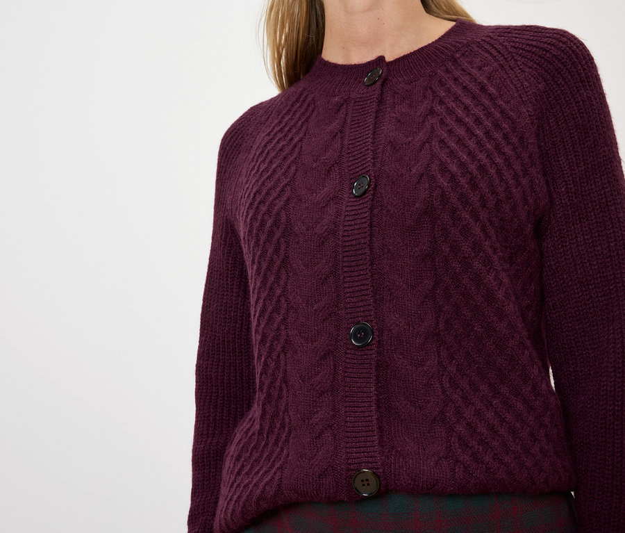 Une femme porte un cardigan violet en tricot.
