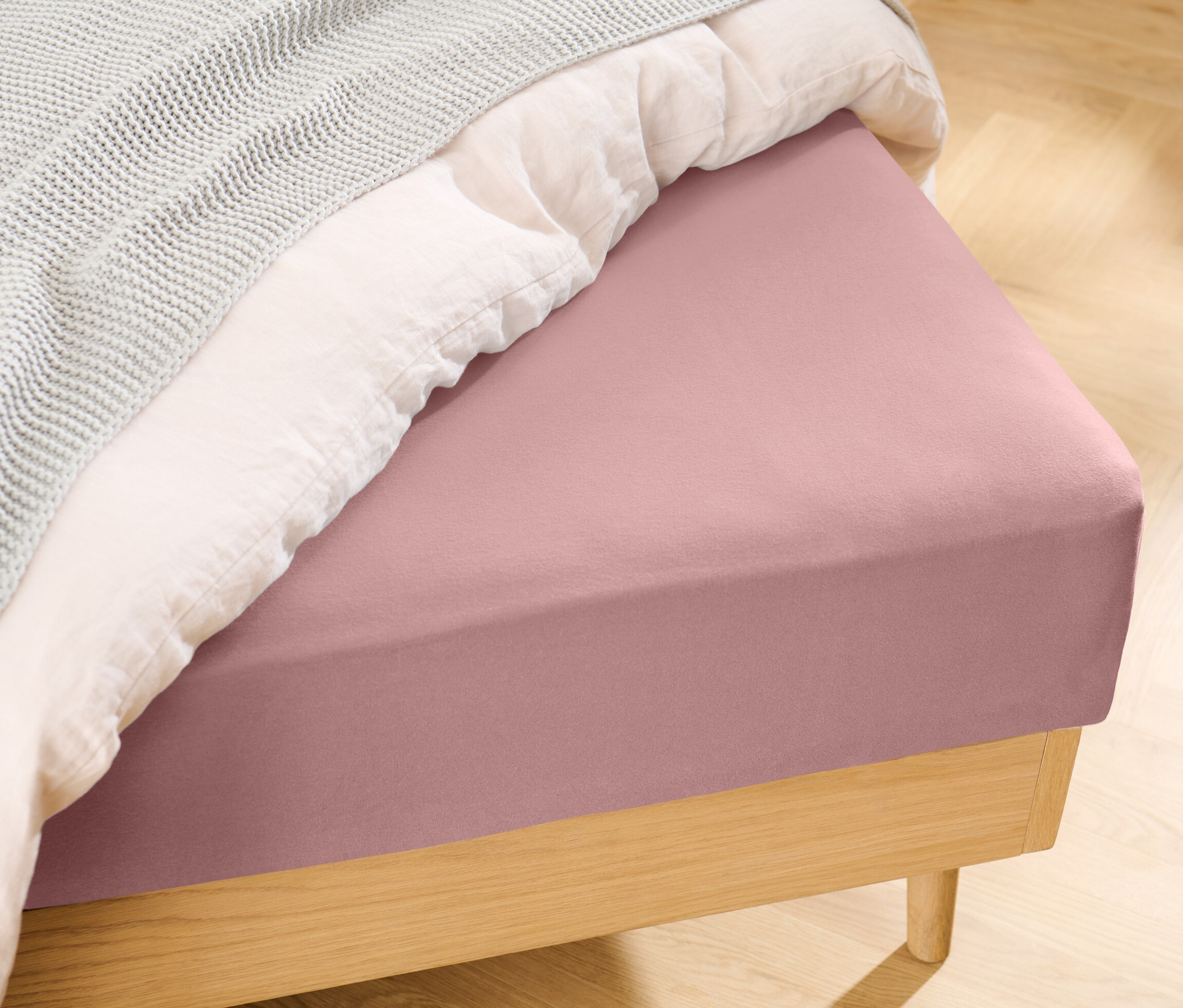 Drap-housse en jersey rose sur un lit.