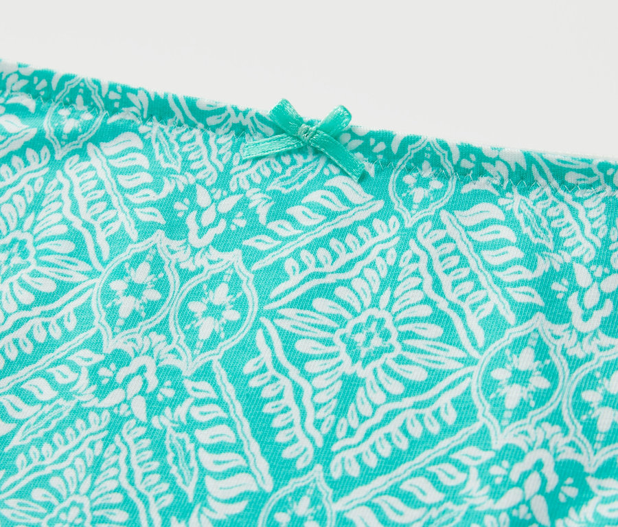 Détail d'une des 7 culottes avec un motif turquoise et blanc et un petit nœud.