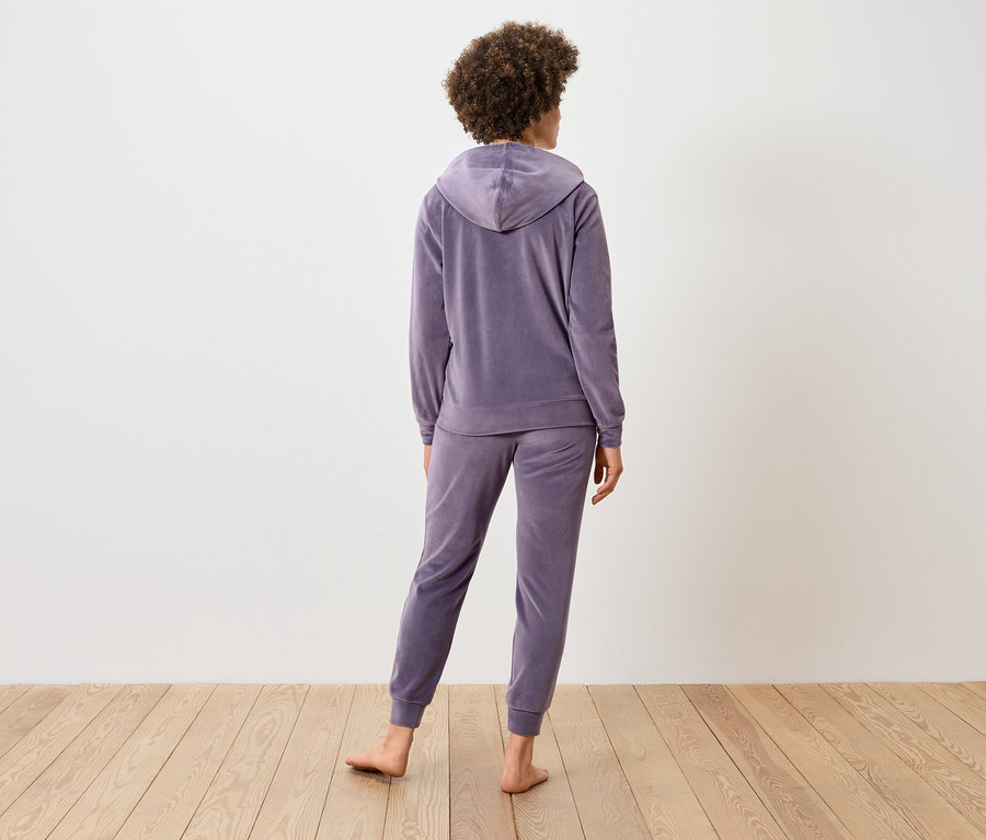 Vue arrière d'une femme aux cheveux bouclés portant un survêtement en velours lilas.