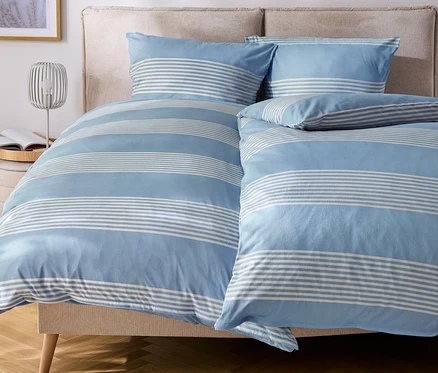 Lit avec des draps et des oreillers rayés bleu et blanc.