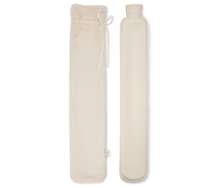 Une longue bouillotte dans une housse en fausse fourrure crème et la bouillotte elle-même à côté.
