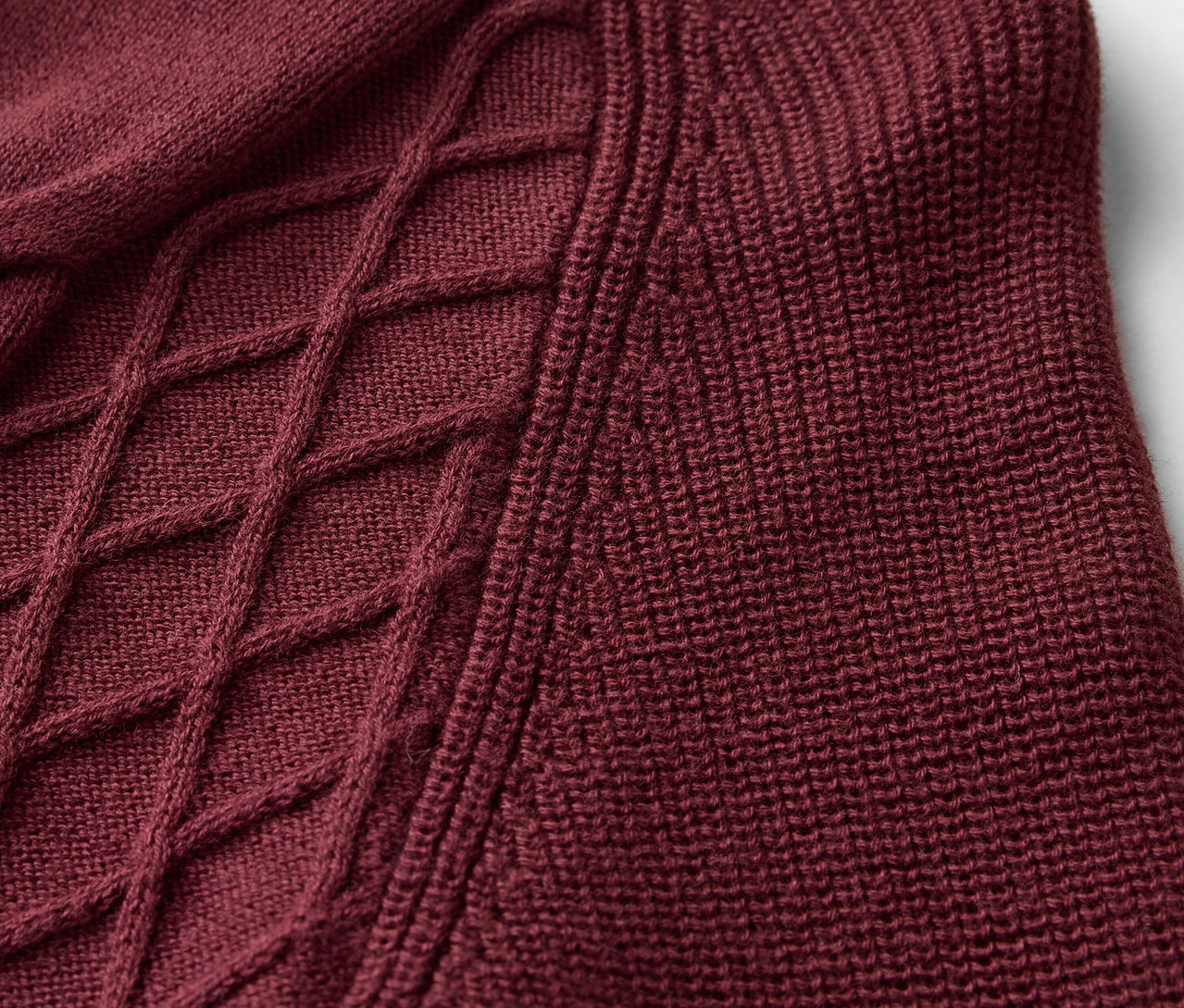 Gros plan sur un pull en tricot bordeaux avec motif torsadé.