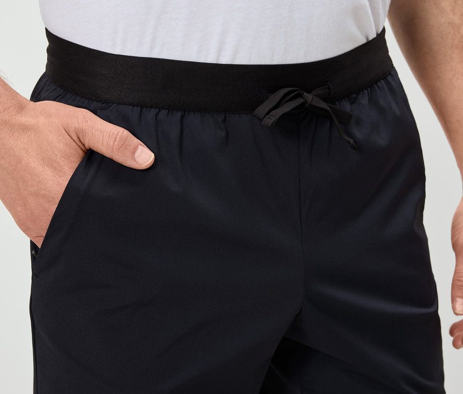 Un homme a la main dans la poche d'un short bleu marine avec une ceinture noire.