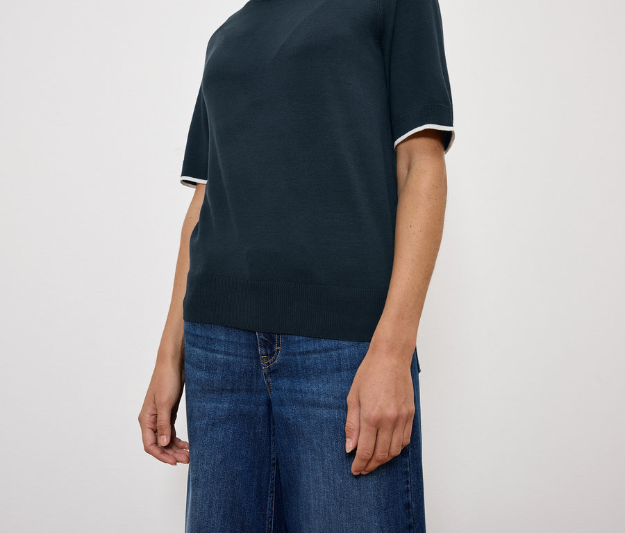 Une femme porte un haut bleu marine à manches courtes et un jean bleu.