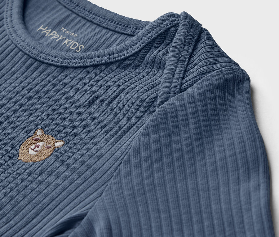 Gros plan sur un t-shirt bleu à manches longues et structure côtelée pour bébé avec broderie d'ours.