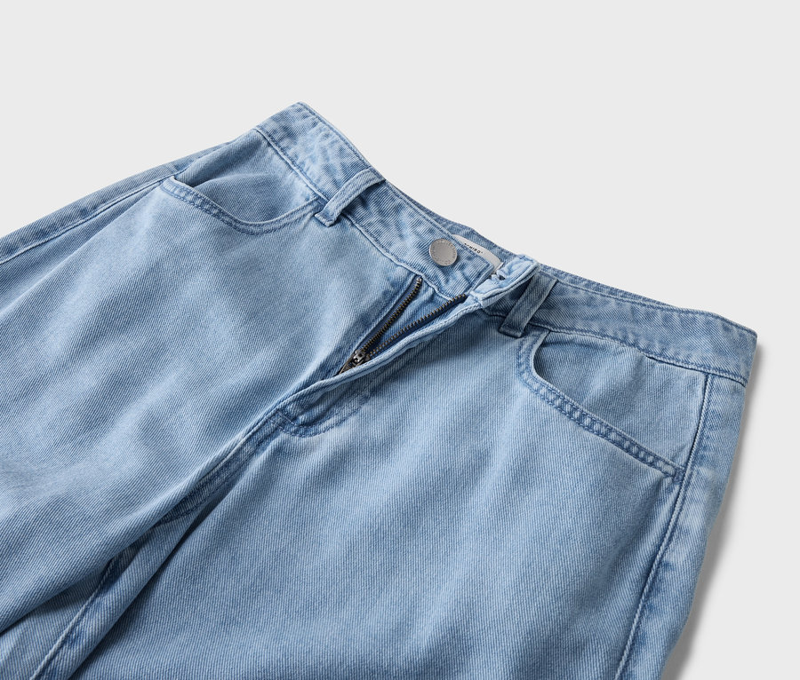 Vue détaillée d'un jean bleu clair avec fermeture éclair et poches apparentes.