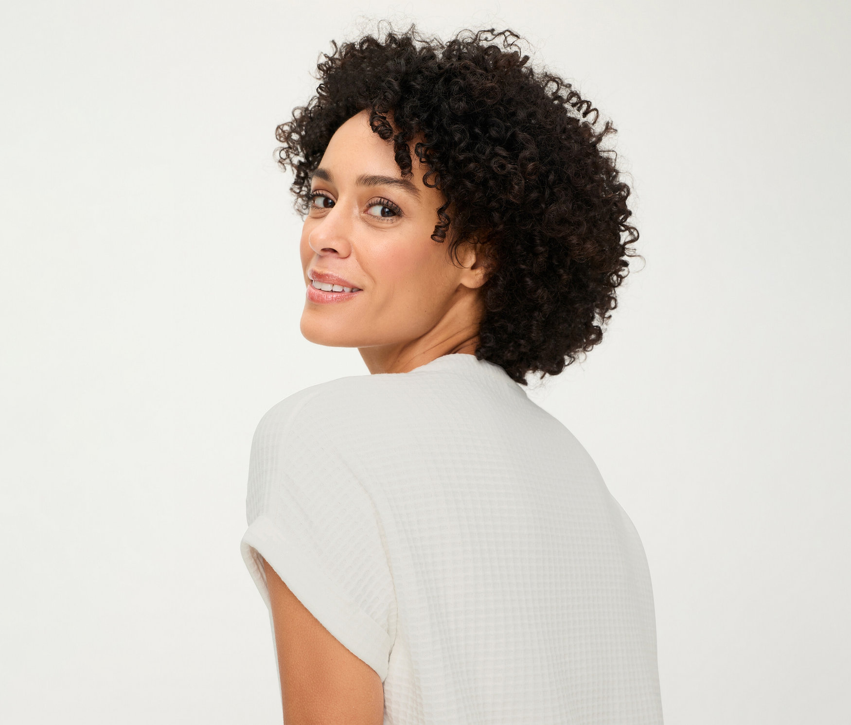 Femme regardant par-dessus son épaule et portant un t-shirt Olsen structuré avec boutons.