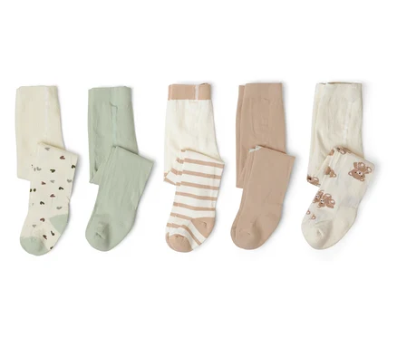 Cinq collants pour enfants pliés en blanc avec des cœurs, vert, blanc rayé, beige et blanc avec des ours sont alignés sur blanc.