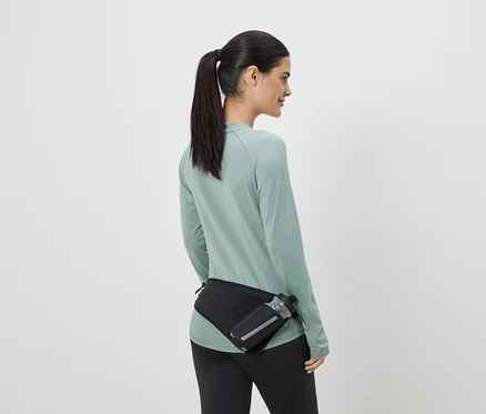 Femme en tenue de sport avec un sac banane noir et une gourde, vue de dos.