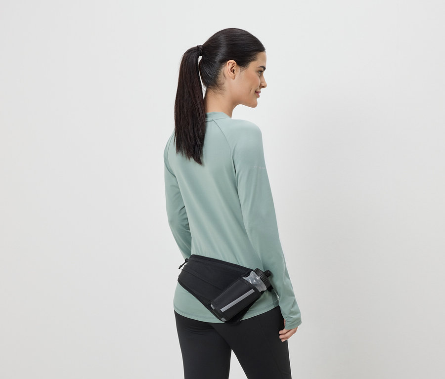 Femme en tenue de sport avec un sac banane noir et une gourde, vue de dos.