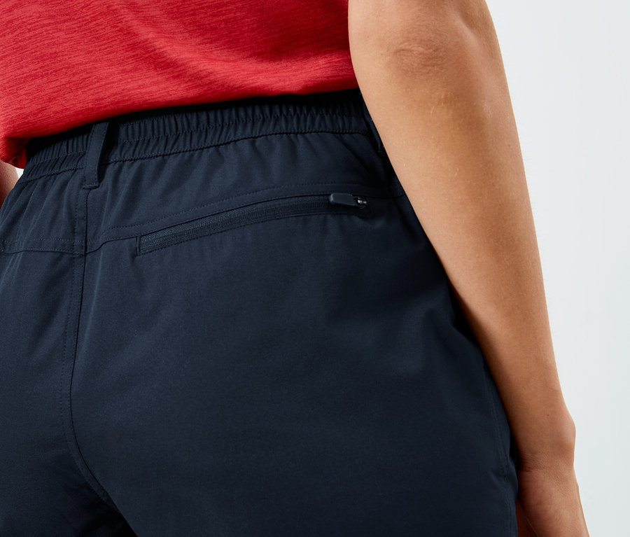 Gros plan sur le dos d'une personne portant un pantalon bleu marine avec une taille élastique et une poche zippée.