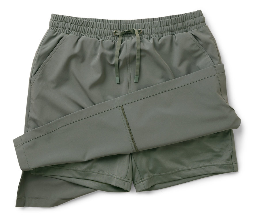 Un pantalon convertible vert olive est plié sur un fond blanc.