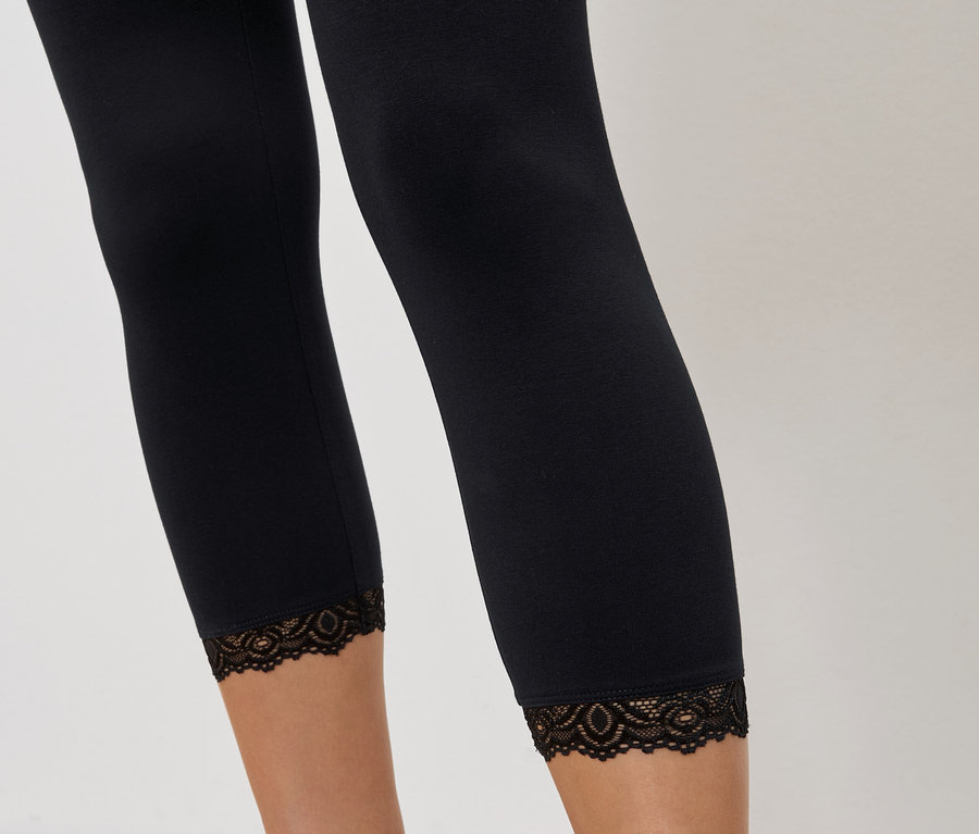 Gros plan sur des jambes portant des leggings noirs avec une bordure en dentelle.