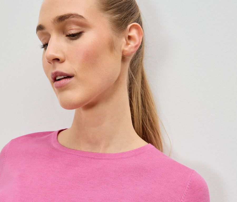 Gros plan d'une femme blonde portant un pull rose.