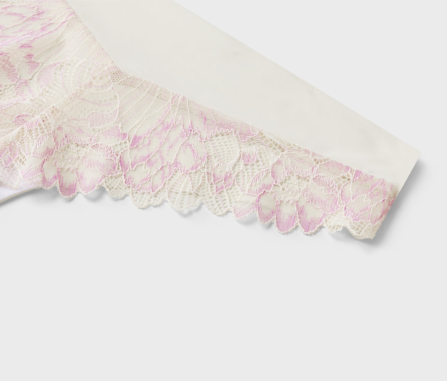 Gros plan sur un tissu blanc avec de la dentelle à motif floral rose sur une manche.