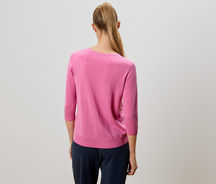 Vue de dos d'une femme aux cheveux blonds attachés en queue de cheval portant un pull rose et un pantalon bleu marine.