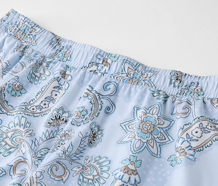 Gros plan d'un pantalon bleu clair à motifs floraux bleus avec une ceinture élastique.