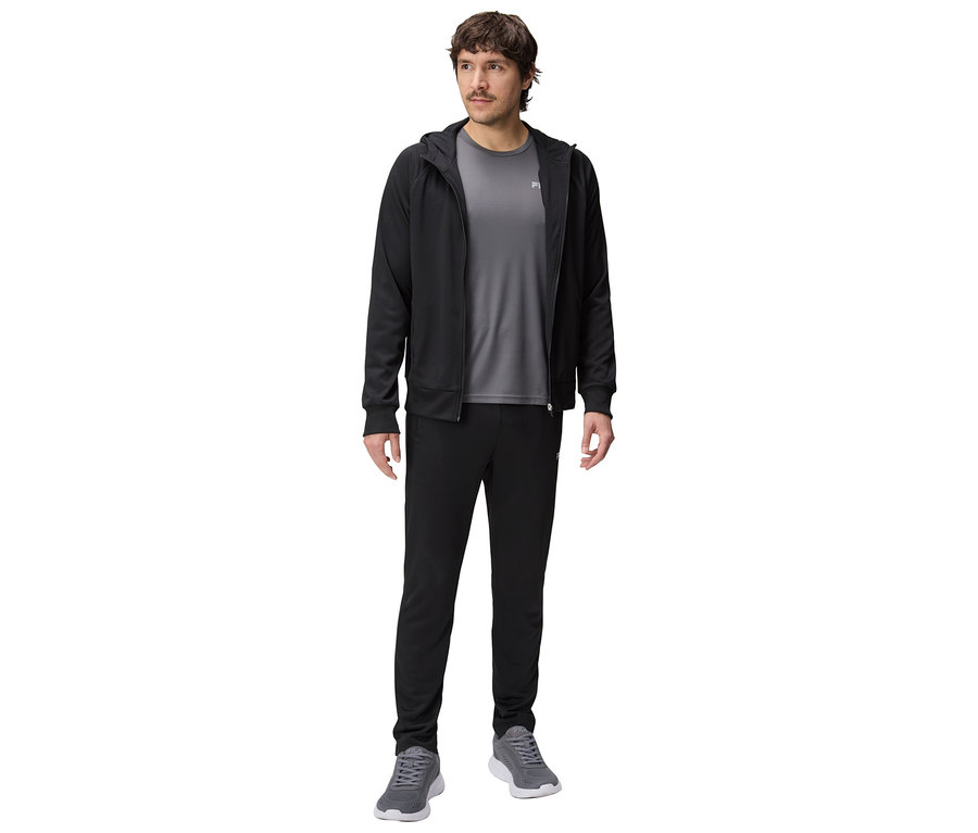 Homme portant un survêtement noir à capuche, un t-shirt gris, un pantalon de survêtement noir et des baskets grises.