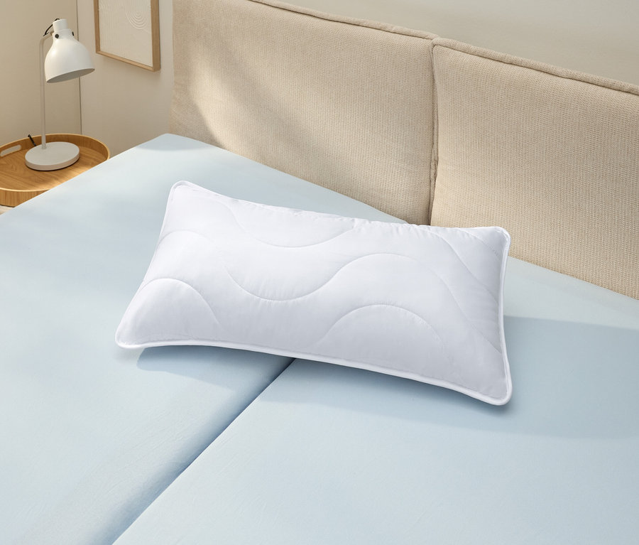 Un oreiller blanc lavable à haute température (env. 80 x 40) est posé sur un drap housse bleu clair.