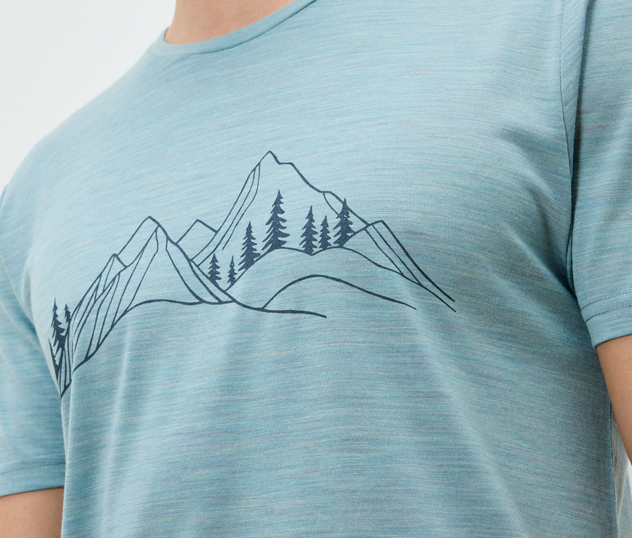 Gros plan d'un t-shirt bleu clair avec une illustration sombre de montagnes et d'arbres.