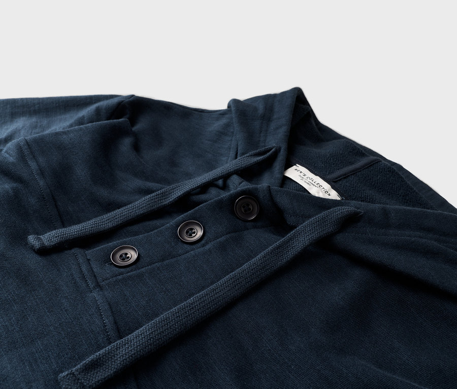 Gros plan d'une chemise bleu marine à manches longues avec trois boutons et un cordon de serrage.