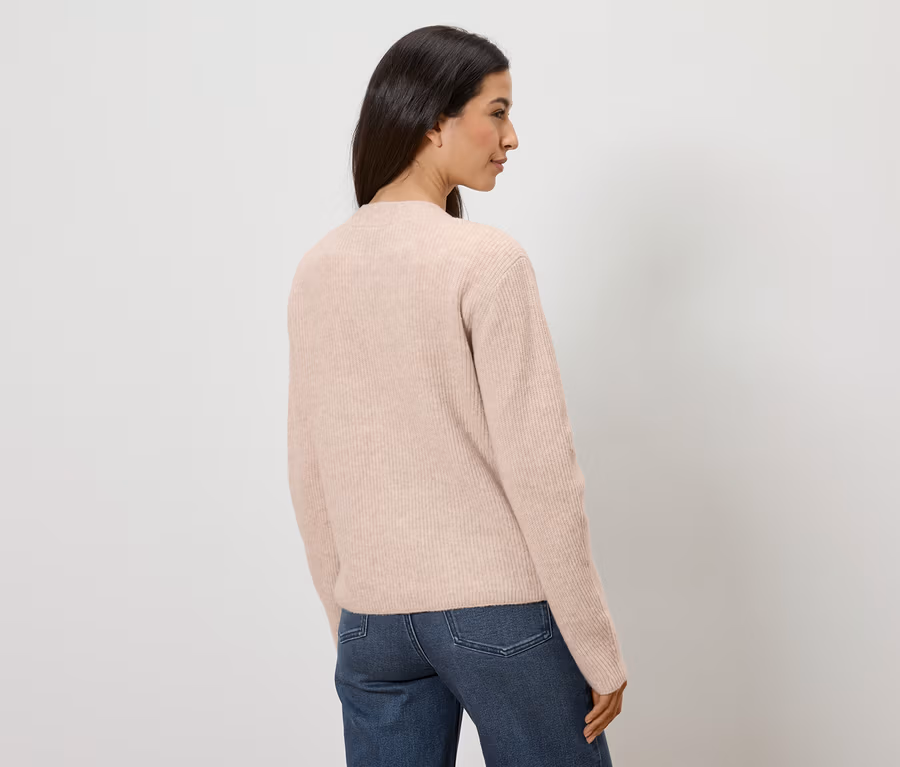 Femme en jean et pull rose, vue de dos sur fond blanc.