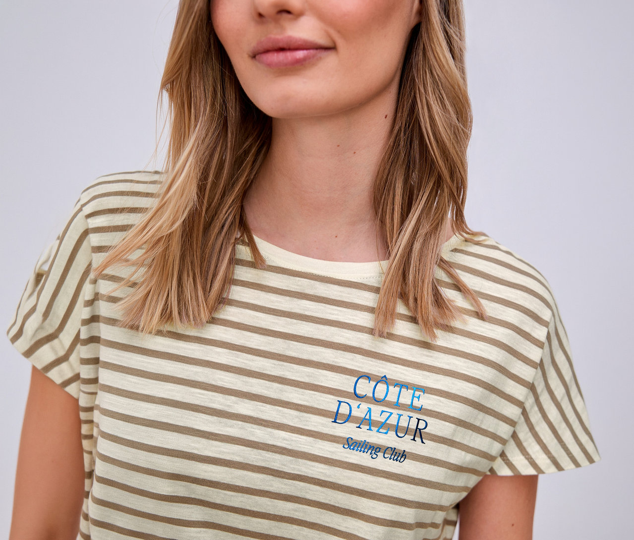 Femme portant un t-shirt Street One, beige et blanc rayé avec l'inscription bleue « Côte d'Azur ».