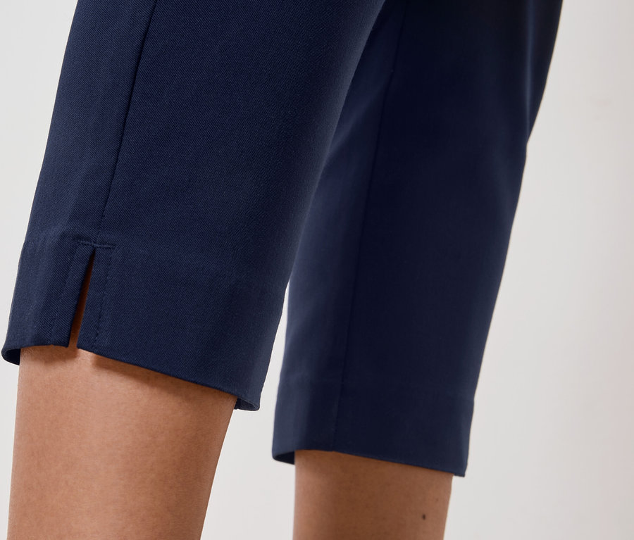 Gros plan des jambes d'une personne portant un pantalon bleu marine avec une fente à l'ourlet.