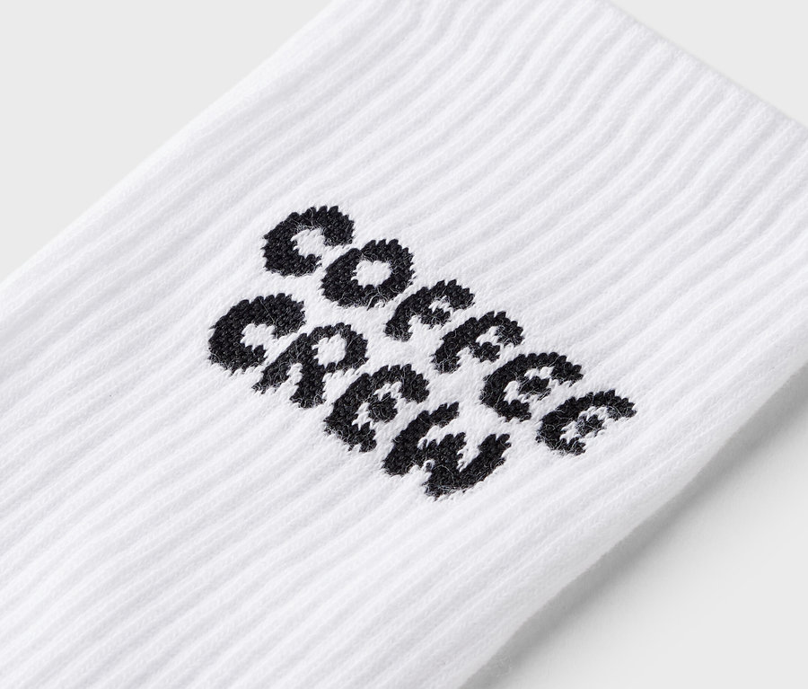 Gros plan d'une chaussette blanche avec l'inscription noire "Coffee Crew".
