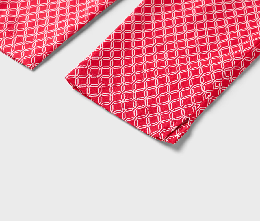 Gros plan sur deux jambes de pantalon rouges avec un motif géométrique blanc.