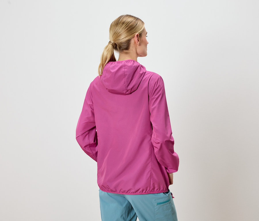 Vue de dos d'une femme blonde portant une veste à capuche rose et un pantalon bleu.