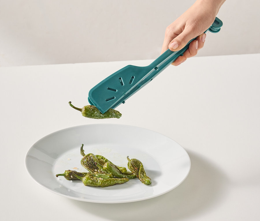 Une main place des poivrons verts dans une assiette à l'aide d'une pince turquoise.