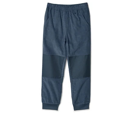 Un pantalon en velours côtelé bleu avec une taille élastique et des pièces aux genoux est posé sur un fond blanc.
