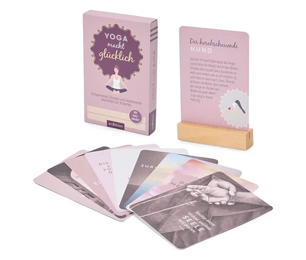 Un jeu de cartes « Yoga rend heureux » avec un support en bois est posé à côté de cartes étalées avec des sagesses de yoga.