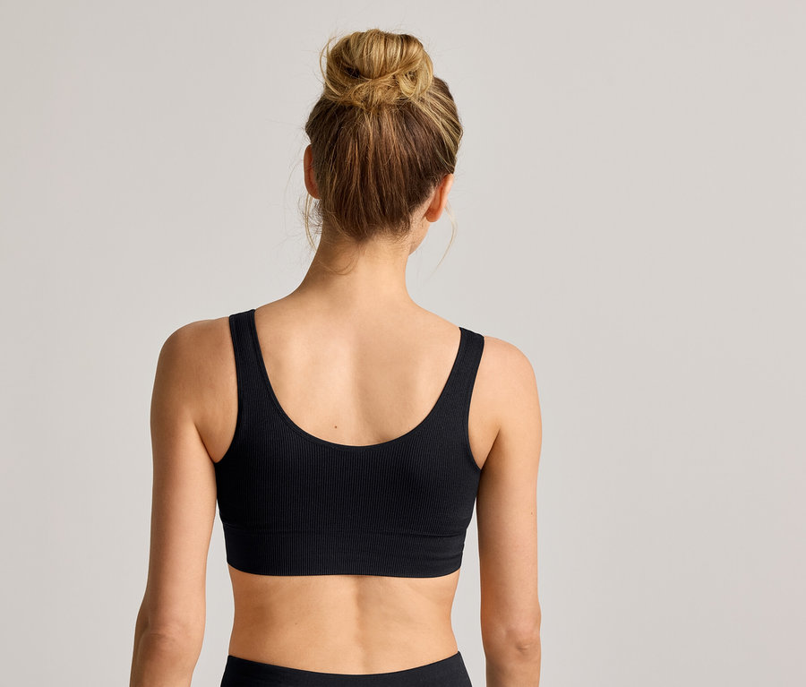 Vue arrière d'une femme portant un chignon et une brassière noire côtelée.