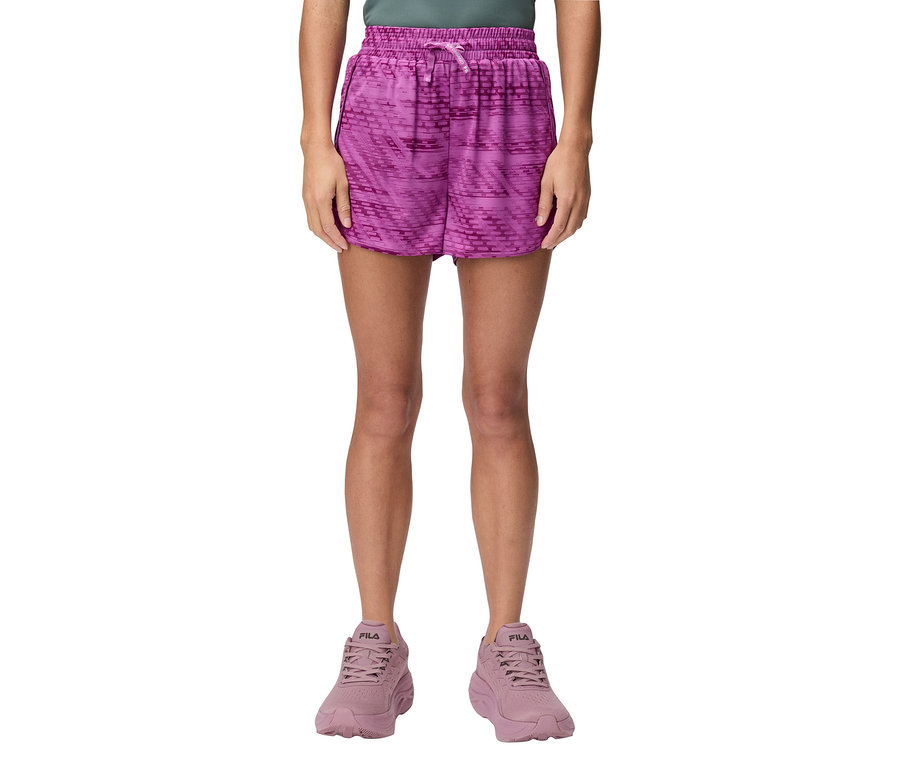 Une femme est debout et porte un short violet et des baskets Fila violettes.