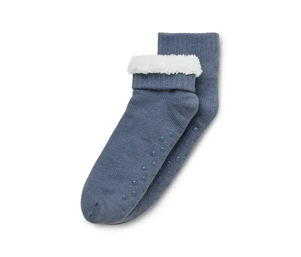 Une paire de chaussettes tricotées bleu-gris avec des revers blancs duveteux et des picots antidérapants sur les semelles.