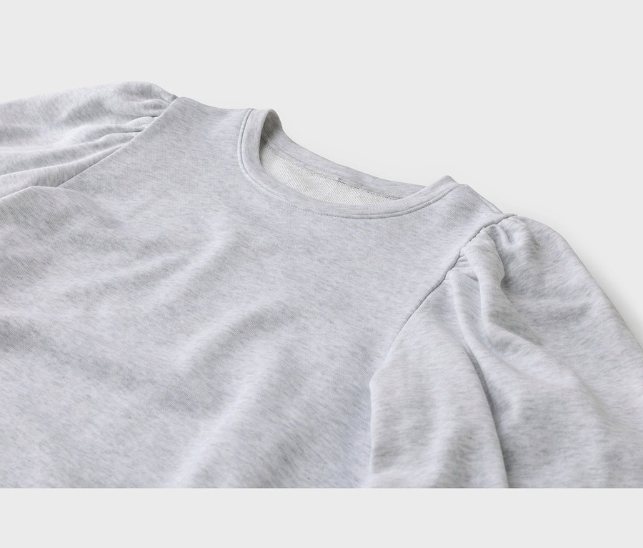 Gros plan d'un sweat-shirt gris clair à col rond et manches bouffantes froncées aux épaules.